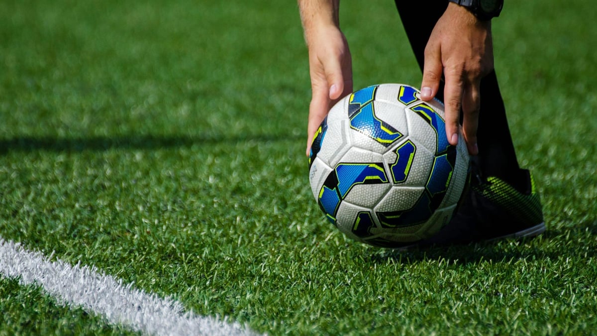 En närbild på en fotbollsspelare som förbereder en frispark. 