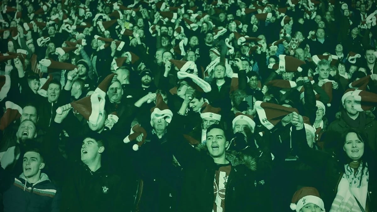 En stor publik på en sportarena firar med tomteluvor och upplyft stämning under en julmatch.