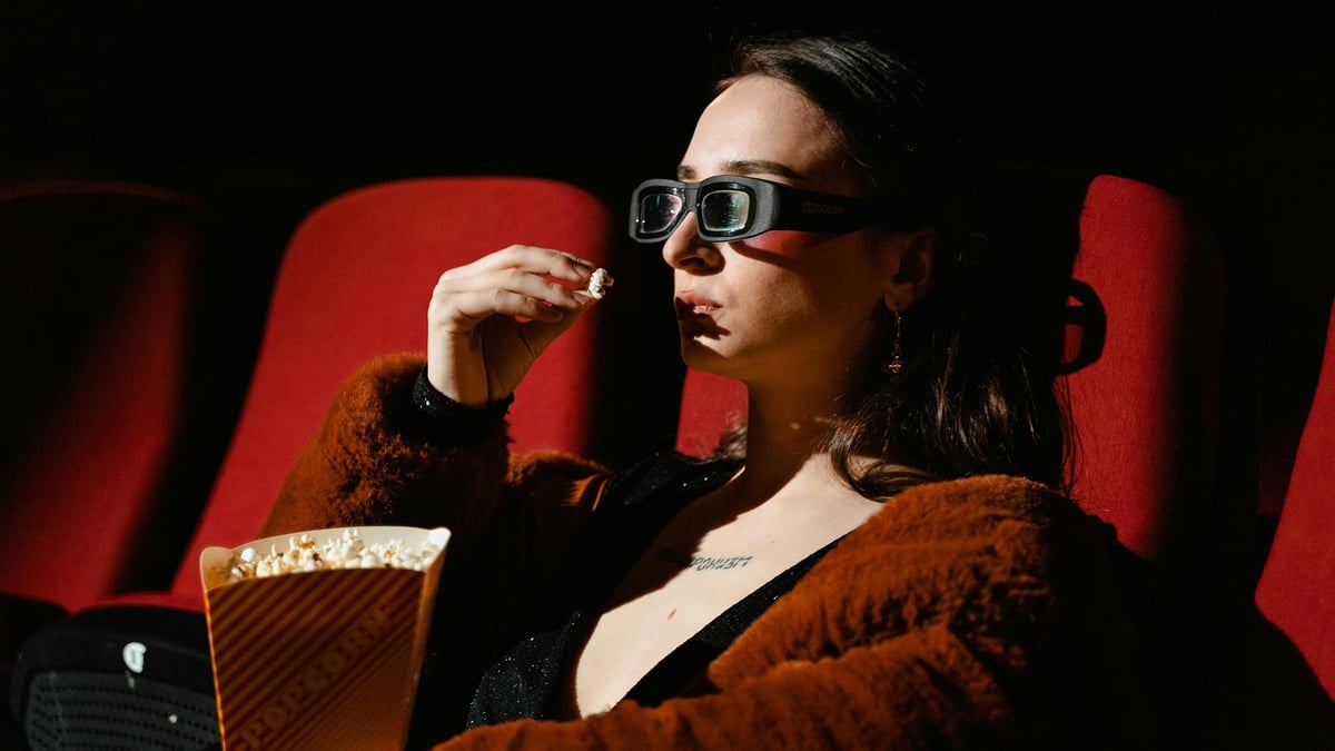 En kvinna äter popcorn och kollar på en Oscarsfilm.