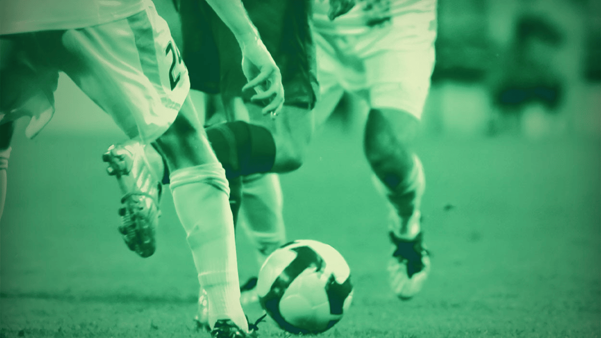 Närbild av en intensiv duell mellan fotbollsspelare som kämpar om bollen under en match.