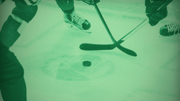 Närbild av en tekning i en ishockeymatch, där två spelare kämpar om pucken med sina klubbor.
